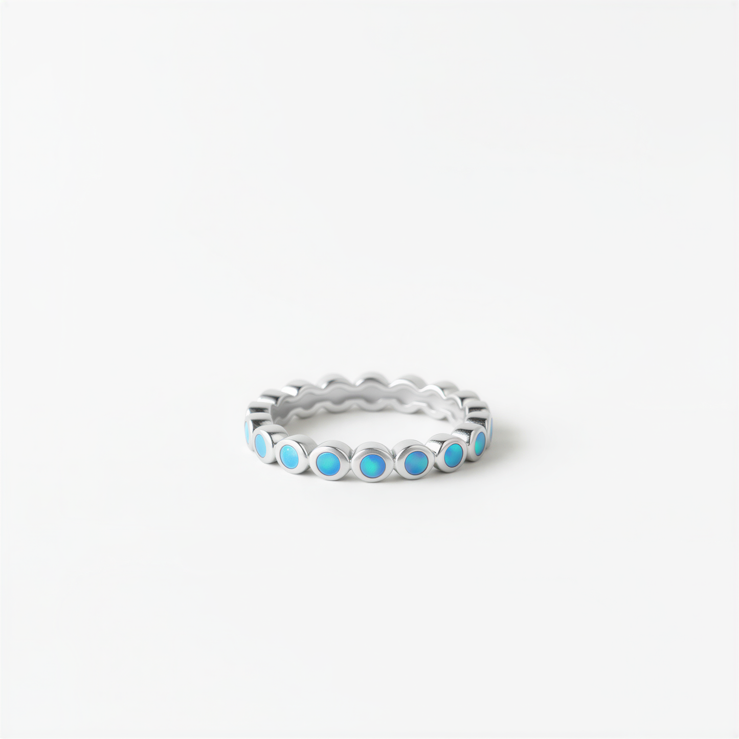 A silver ring with blue stones set in a scalloped design.