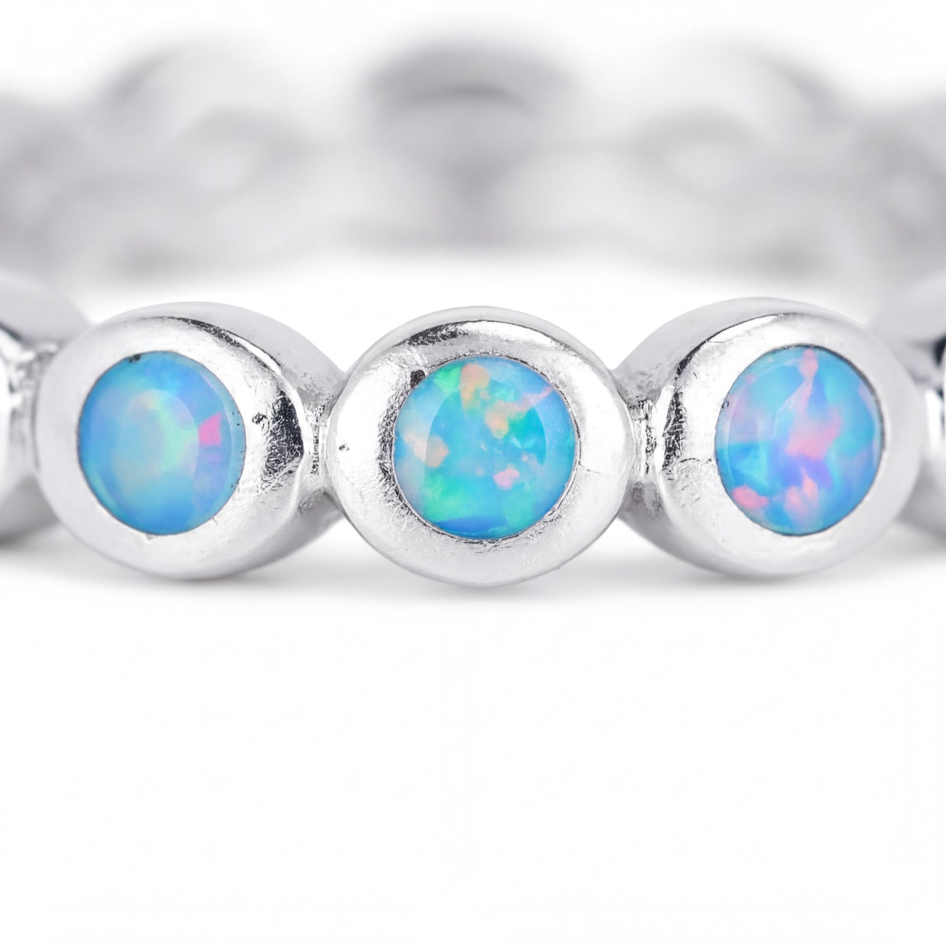 A close-up image of a silver ring with three blue opals set in the center.